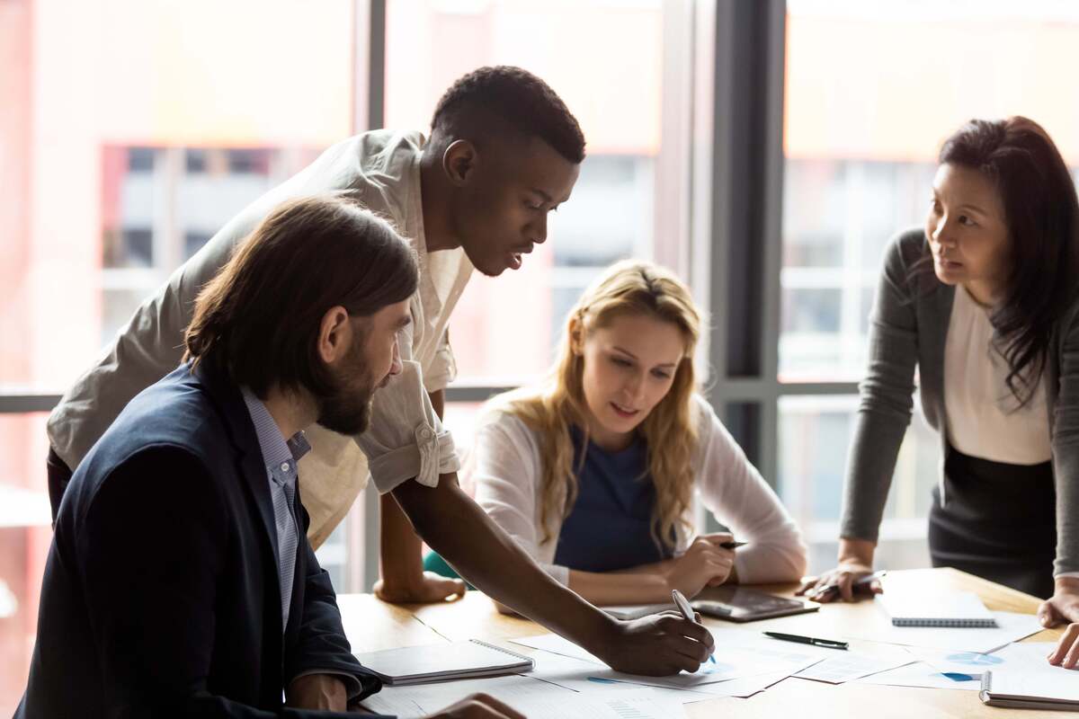 Diverse team collaborating around table in a meeting analyzing reports